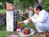 Cô Năm đang thắp nhang ở các ngôi mộ