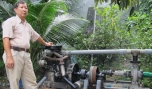 Ông Lê Phước Lộc và hệ thống tưới sử dụng péc phun vừa được ông cải tiến ở bộ phận truyền động.