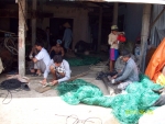 Ngư dân Gò Công vá lưới chuẩn bị ra khơi đánh bắt hải sản.
