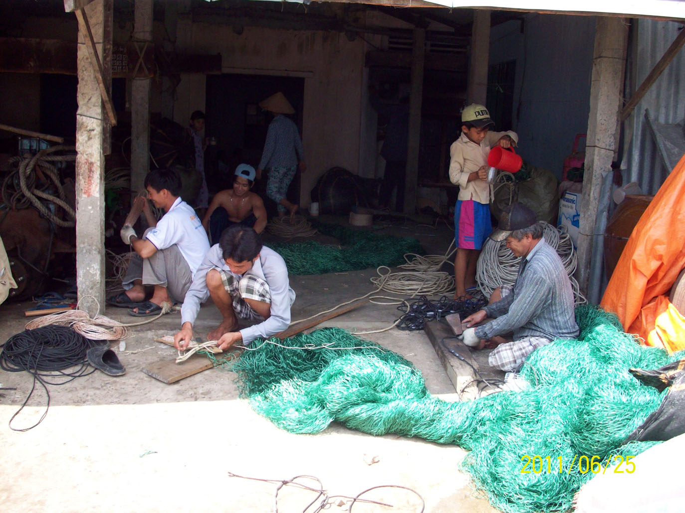 Ngư dân Gò Công vá lưới chuẩn bị ra khơi đánh bắt hải sản.