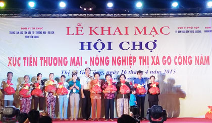 Ông Nguyễn Tấn Hùng, Tỉnh ủy viên - Bí thư Thị ủy Gò Công và bà Lê Thị Trang,Trưởng Ban Phong trào - Ủy ban Mặt trận Tổ quốc Việt Nam tỉnh Tiền Giang tặng quà cho hộ nghèo tại lễ khai mạc Hội chợ Xúc tiến Thương mại – Nông nghiệp thị xã Gò Công năm 2015. (Ảnh: Danh Hiếu)