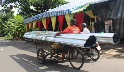 Mô tô đẩy xe ba gác chở hàng cồng kềnh trên đường tỉnh 868 (xã Mỹ Phước Tây, huyện Cai Lậy).