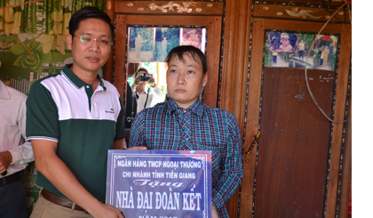 Ông Chử Văn Nam, Phó Giám đốc Vietcombank Tiền Giang trao bảng tượng trưng nhà đại đoàn kết cho đại diện gia đình anh Phạm Văn Cường