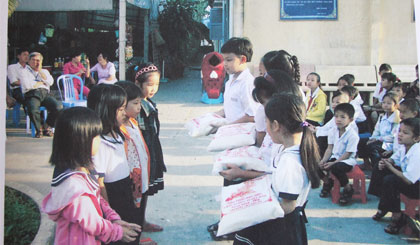 Các em trao gạo cho nhau trong phong trào “nụ cười hồng”.