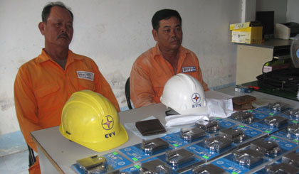 Hai nhân viên điện lực dỏm cùng tang vật tại cơ quan công an.