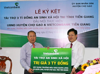 Ông Ngô Minh Nhựt, Giám đốc Vietcombank Tiền Giang (bên phải) trao gói tài trợ ASXH cho Ông Lê Văn Mỹ, Chủ tịch UBND huyện Chợ Gạo.