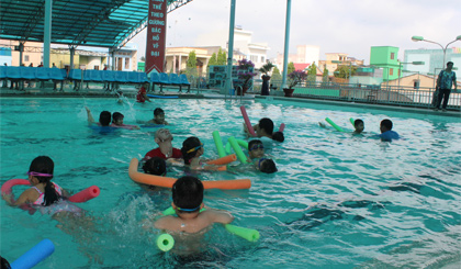 Các huấn luyện viên tập bơi cho các em học sinh.